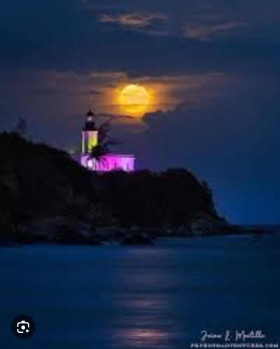 a lighthouse at night with the moon in the background at Sunrise in Villas del Faro in Emajagua