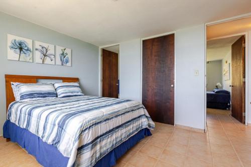 a bedroom with a bed with a striped comforter at Sunrise in Villas del Faro in Emajagua