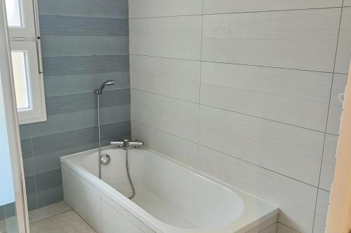 La salle de bains est pourvue d'une baignoire blanche et d'une fenêtre. dans l'établissement Maison MANGUELI - Bassin d 'Arcachon, à Audenge