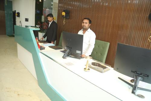 two men sitting at a desk with a laptop computer at Geetanjali International Annex a unit of Geetanjali International in Deoghar