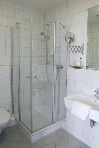 a bathroom with a glass shower and a sink at business & conference Sporthotel Großwallstadt in Großwallstadt