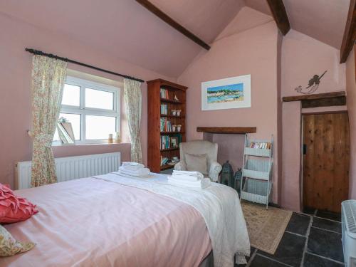 a bedroom with a bed and a window and a chair at Melin Rhos Farm in Penrhos-Lligwy