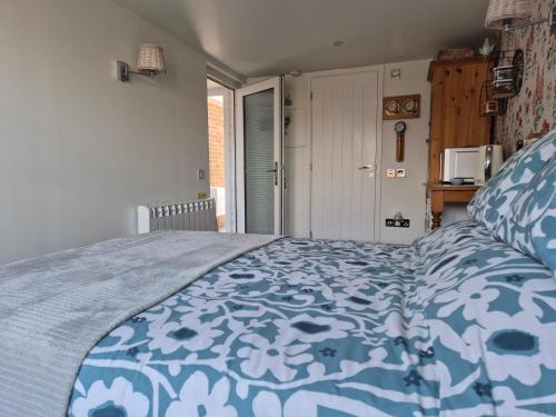 a bedroom with a bed with a blue and white comforter at Flower Garden Studio in Sheringham-Cycle friendly in Sheringham