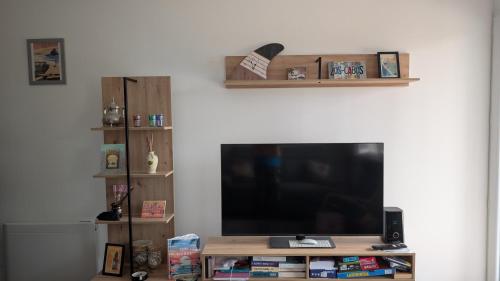- un salon avec une télévision à écran plat et des étagères dans l'établissement Appartement avec jardin proche de l'océan, à Saint-Julien-en-Born
