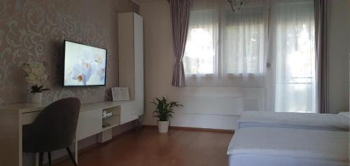 a bedroom with a bed and a desk and a window at Orchidea Apartman in Gödöllő