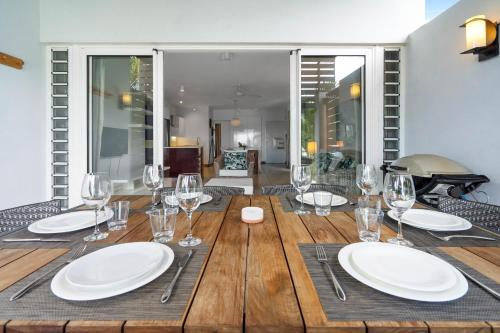 a wooden table with plates and wine glasses on it at Kanope Bay - Holiday Beachfront Apartments in Pointe aux Biches