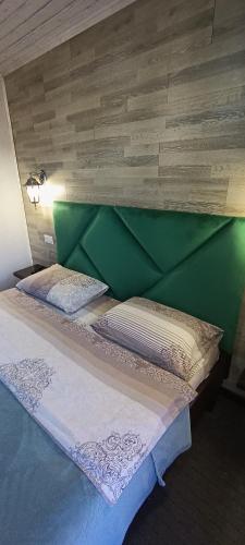 a bed with a green headboard and pillows on it at Садиба Янчар Номер Студiо з Басейном in Mykulychyn