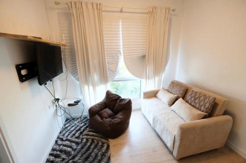 a living room with a couch and a window at 7min BKK airport - free pick up - malls nearby in Bangkok