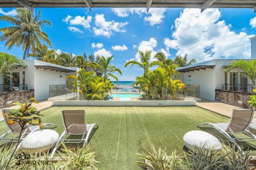 an exterior view of a house with a lawn and chairs at Kanope Bay - Holiday Beachfront Apartments in Pointe aux Biches