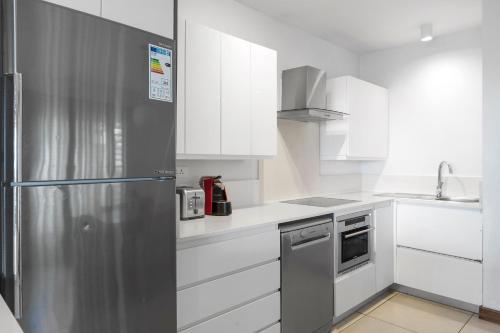 a kitchen with white cabinets and a stainless steel refrigerator at Kanope Bay - Holiday Beachfront Apartments in Pointe aux Biches