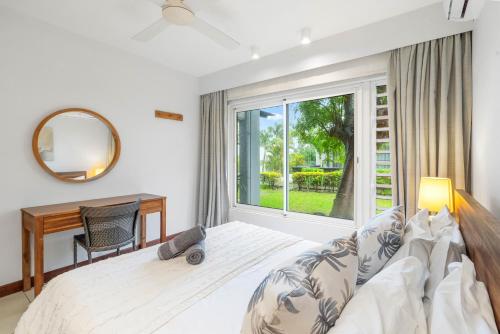 a bedroom with a bed and a desk and a window at Kanope Bay - Holiday Beachfront Apartments in Pointe aux Biches
