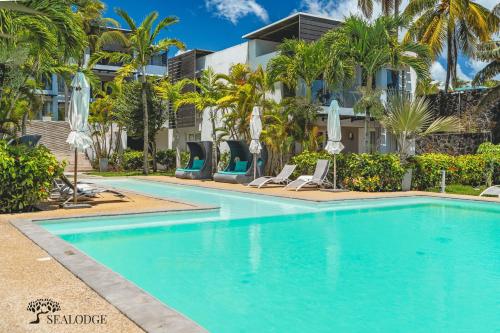 a swimming pool in front of a building with palm trees at Kanope Bay - Holiday Beachfront Apartments in Pointe aux Biches