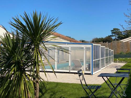 une maison en verre avec un palmier dans une cour dans l'établissement Maison familiale avec piscine privée à Saint-Vincent-sur-Jard - FR-1-336-136, à Saint-Vincent-sur-Jard