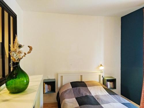 un vase vert assis sur une table à côté d'un lit dans l'établissement Appartement cosy au cœur du village historique, à Saint-Jean-Pied-de-Port