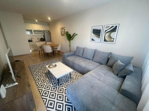 een woonkamer met een blauwe bank en een tafel bij Vista City Apartment in Podgorica