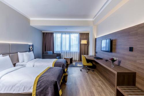 a hotel room with two beds and a desk at Nearport Hotel Sabiha Gokcen Airport in Istanbul