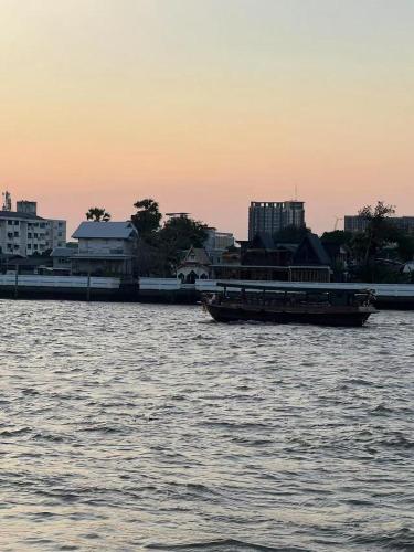 a river with two boats in the water with buildings at JC home 刘 先 生 in Bangkok