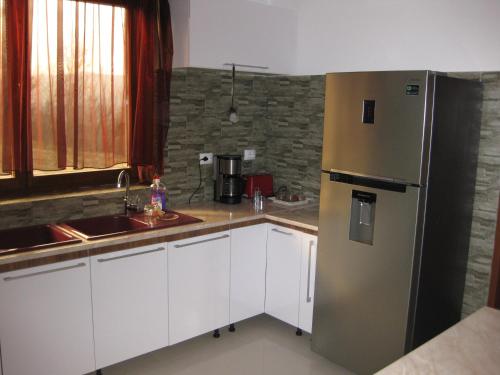 a kitchen with white cabinets and a stainless steel refrigerator at Pensiunea Agroturistica Diana in Măgura