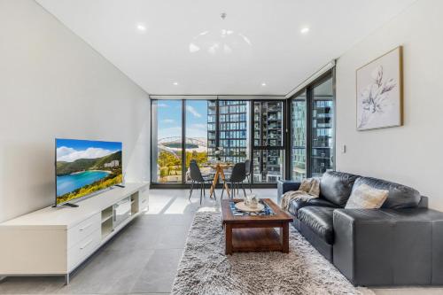 a living room with a couch and a tv at New 2BR Apartment in Olympic Park Near Stadium in Sydney