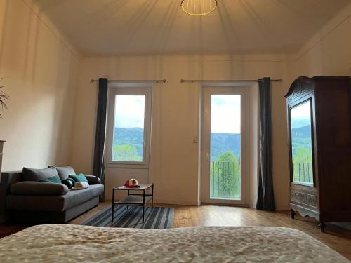 a bedroom with a bed and a couch and two windows at Maison calme in Seyne