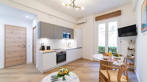 une cuisine avec des armoires blanches et une table et une salle à manger dans l'établissement B G Cocon Meyerbeer - Grimaldi Promenade des Angla, à Nice