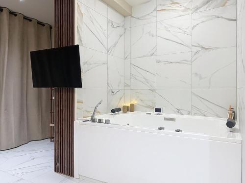 a bathroom with a tub and a tv on a wall at V' Appart SPA Moderne-Chic in Troyes