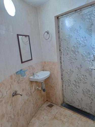 a bathroom with a shower with a sink and a shower door at Kottai Veedu Pondicherry in Pondicherry