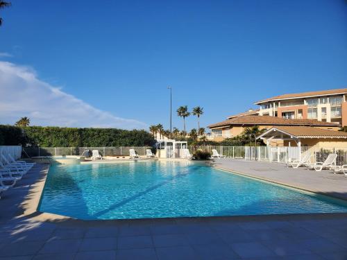 une grande piscine avec des chaises et un bâtiment dans l'établissement CAP HERMES, Magnifique Vue mer pour ce studio 33m2, à Fréjus