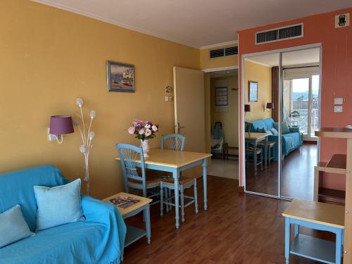 un salon avec un canapé bleu et une table dans l'établissement CAP HERMES, Magnifique Vue mer pour ce studio 33m2, à Fréjus