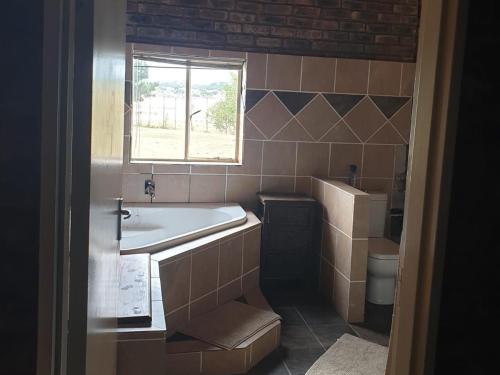 een badkamer met een bad, een wastafel en een raam bij Uitzicht Guest Farm in Kroonstad