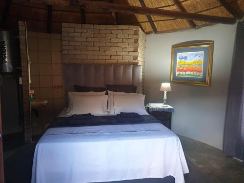 een slaapkamer met een groot bed met witte lakens bij Uitzicht Guest Farm in Kroonstad