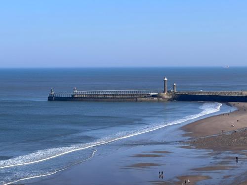 a pier in the ocean with people walking on the beach at The Wheeldale in Whitby