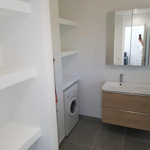 une salle de bain avec une machine à laver et un lavabo dans l'établissement Bel appartement 2 pièces rénové proche plages rez de jardin, à Cavalaire-sur-Mer