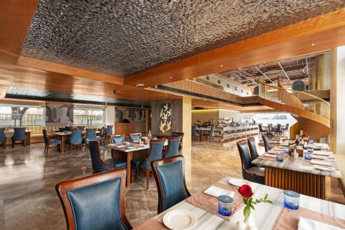 a restaurant with wooden floors and tables and chairs at Auradoon, Dehradun - By Leisure Hotels in Dehradun