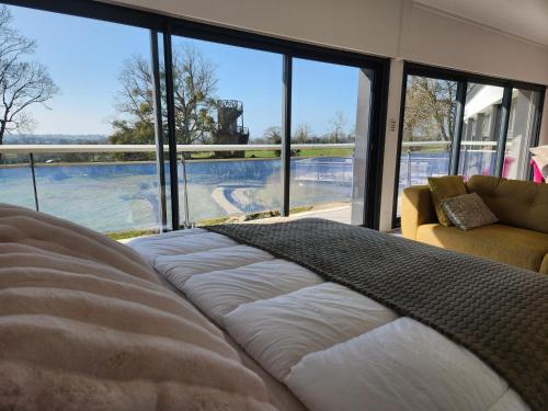 un grand lit dans une chambre avec une grande fenêtre dans l'établissement La Villa de Louis, à Saint-Planchers