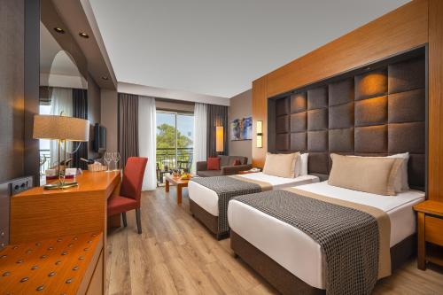 a hotel room with two beds and a desk at Gravel Hotels Select - Ultra All Inclusive in Kemer