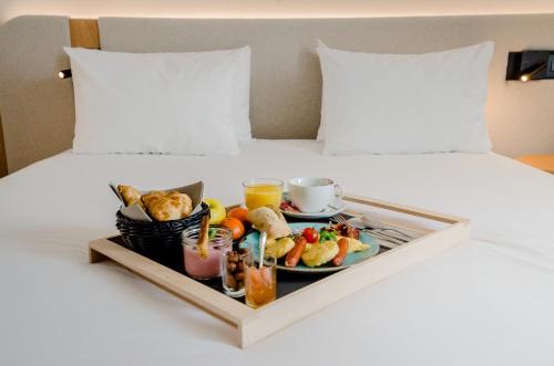 a tray of breakfast food on a bed at Golden Tulip Villepinte Roissy - Parc des Expositions in Roissy-en-France