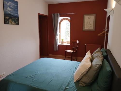 a bedroom with a blue bed with a window at Auberge La Tournelle in Saint-Jean-de-Valériscle