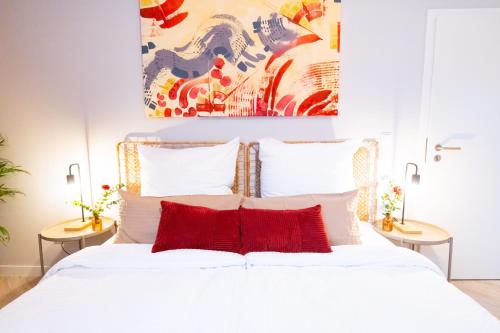 ein Schlafzimmer mit einem weißen Bett mit roten Kissen in der Unterkunft BetterBeds Essen in Essen