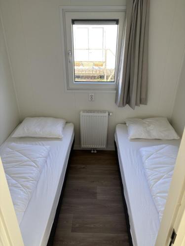 two beds in a small room with a window at Chalet Lutafaro near beach Petten in Petten