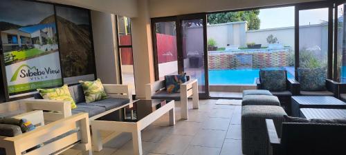a living room with couches and chairs and a pool at Glamping At Sibebe View Villa in Mbabane
