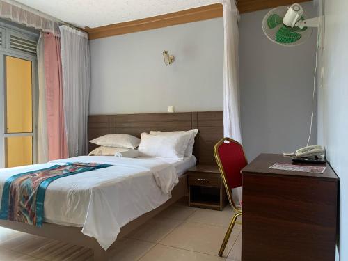 a bedroom with a bed and a desk with a phone at Agenda 2000 Hotels Ltd in Kampala