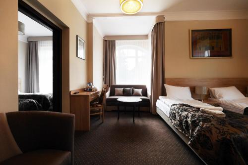 ein Hotelzimmer mit einem Bett, einem Stuhl und einem Schreibtisch in der Unterkunft Willa San Remo in Kudowa-Zdrój