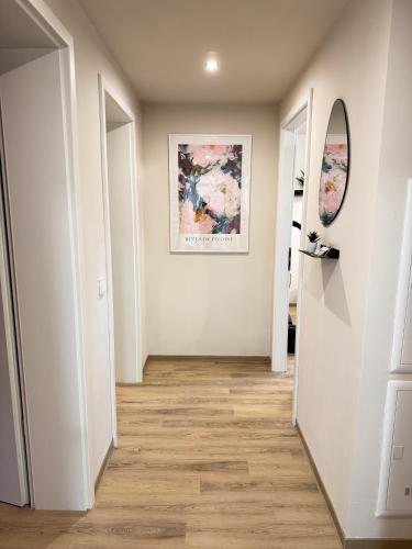 a hallway with white walls and wooden floors and a mirror at LIGHTPLACE • Design • Boxspring • Balkon • 2 Smart TV •Innenstadt in Braunschweig