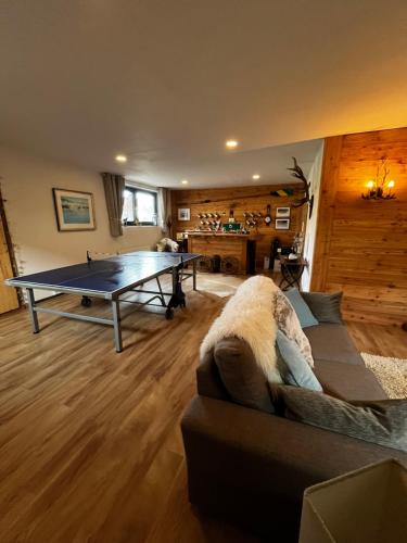 a living room with a couch and a ping pong table at Luxury Chalet Suite suitable for 4 Guests, Living Room, Kitchen and Games Room in Tamsweg