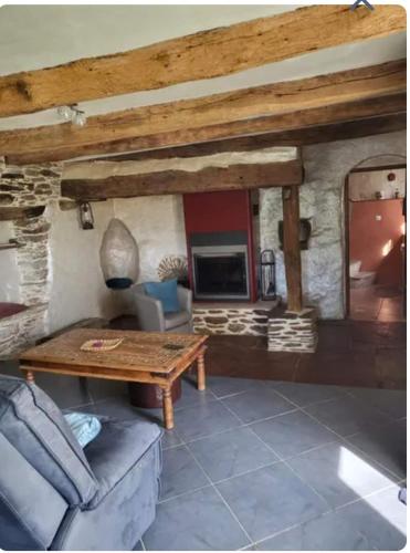 - un salon avec une table et une cheminée en pierre dans l'établissement La Maison du chataignier, à Cassagnolles