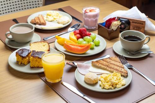 een tafel met borden ontbijtproducten en kopjes koffie bij Pousada Cachoeira da Barra in Cunha