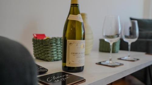 a bottle of wine sitting on a table with two glasses at Spacious Bromley Home w Free parking and Outside Dining in Bromley