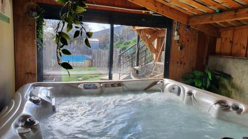 - un bain à remous dans une maison avec fenêtre dans l'établissement Gîte de Pied Chapel - Piscine, spa et pleine nature, à Alba-la-Romaine