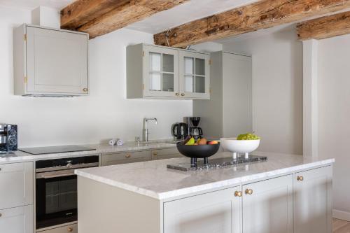 a kitchen with white cabinets and a bowl of fruit on a counter at Stylish loft in the heart of CPH in Copenhagen